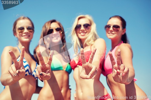 Image of group of smiling young women on beach