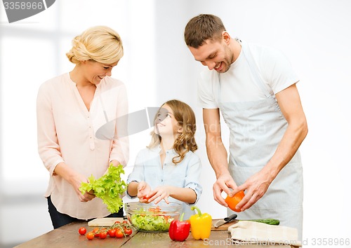 Image of happy family cooking vegetable salad for dinner