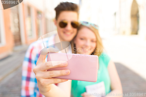 Image of happy couple taking selfie with smartphone in city