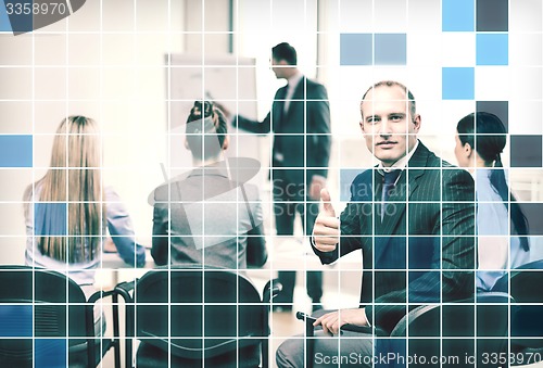 Image of businessman with team showing thumbs up in office