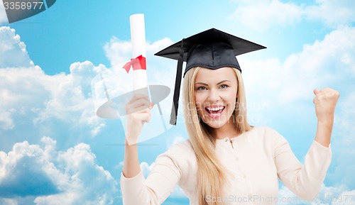 Image of student in trencher cap with diploma over blue sky