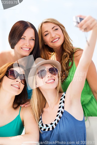 Image of girls taking photo in cafe on the beach