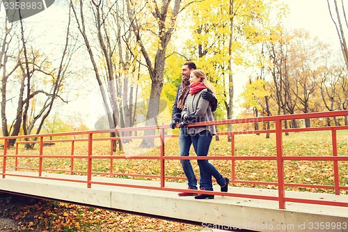 Image of smiling couple hugging on bridge in autumn park
