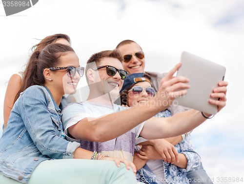 Image of group of smiling teenagers looking at tablet pc