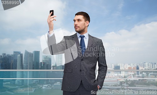 Image of young businessman with smartphone over city