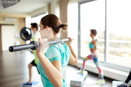 Image of close up of people exercising with bars in gym