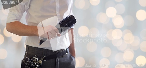 Image of close up of male stylist with brush at salon