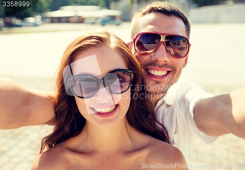 Image of smiling couple wearing sunglasses making selfie