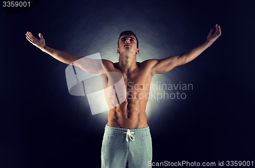Image of young male bodybuilder with raised hands