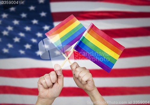 Image of hands with rainbow flags over american background