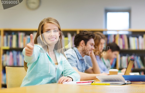 Image of happy student girl showing thumbs up in library