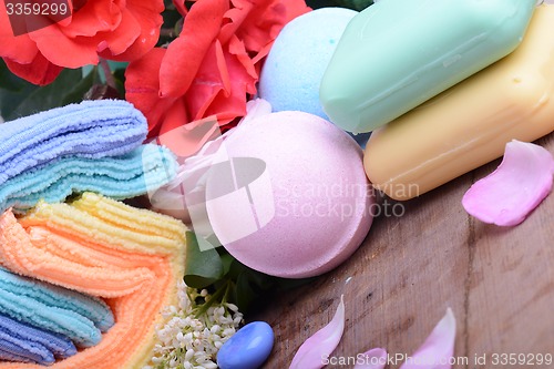 Image of Towels with lily, aroma oil,  candles and sea salt on wooden plate