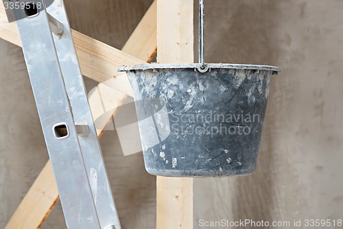 Image of Dirty bucket and ladder on wall background