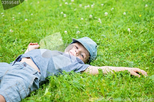 Image of Little caucasian boy resting on grass