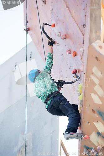 Image of Man climbs upward on ice climbing competition