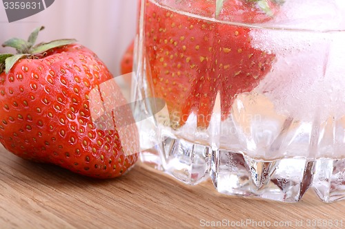 Image of Strawberry on wooden plate and strawberry frozen with ice in cup