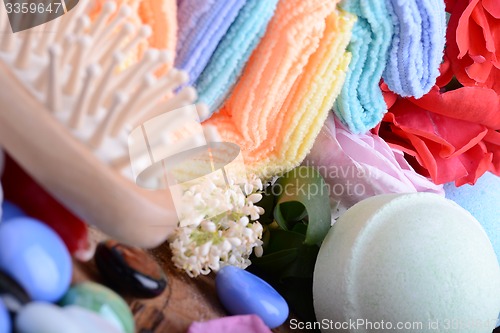 Image of sea salt, spa stones towels and rose flower petals on wooden table, close up. Relax and treatment therapy. Summer season. 