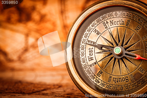 Image of Vintage compass lies on an ancient world map.