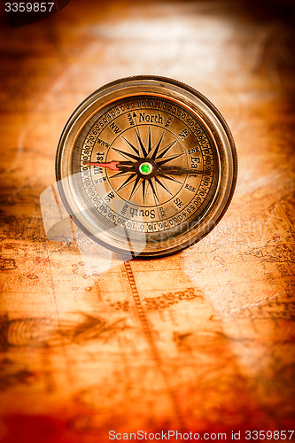 Image of Vintage compass lies on an ancient world map.