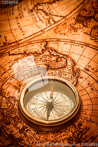 Image of Vintage compass lies on an ancient world map.