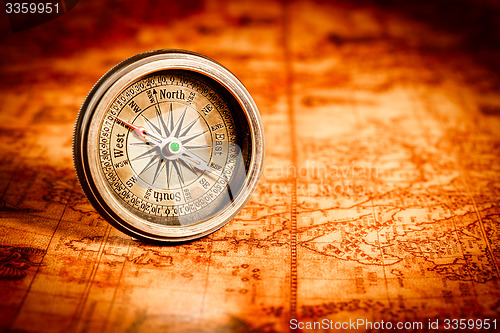 Image of Vintage compass lies on an ancient world map.