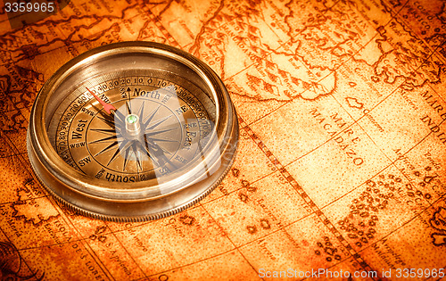 Image of Vintage compass lies on an ancient world map.