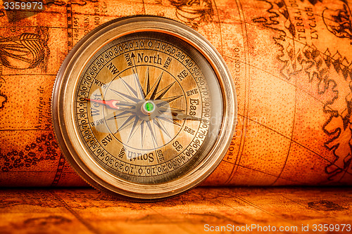 Image of Vintage compass lies on an ancient world map.