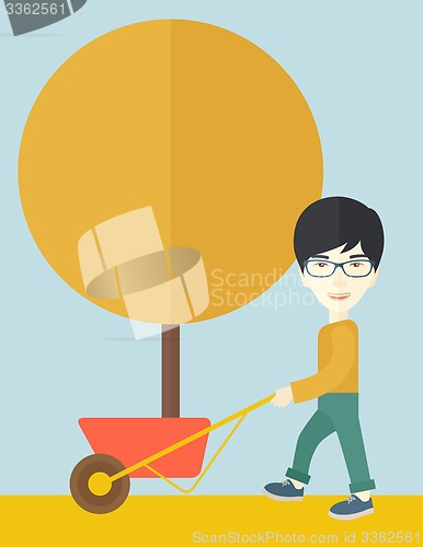 Image of Young man pushing the cart with tree.