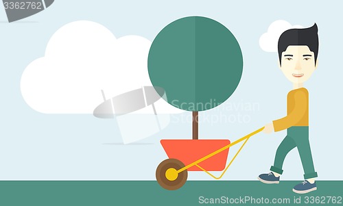 Image of Young man pushing the cart with tree.