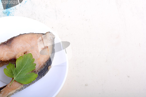 Image of Frying pan with one roasted salmon steaks, view from above