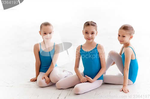 Image of Three little ballet girls sitting and posing together