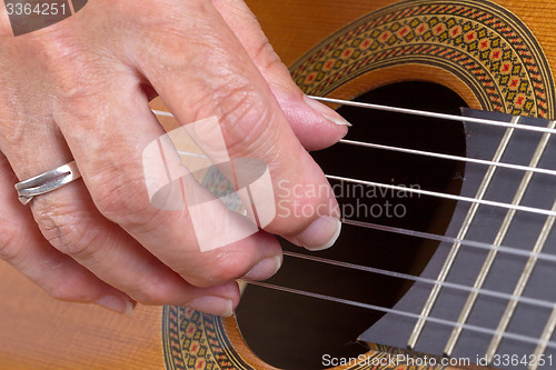 Image of Old woman\'s hand playing guitar