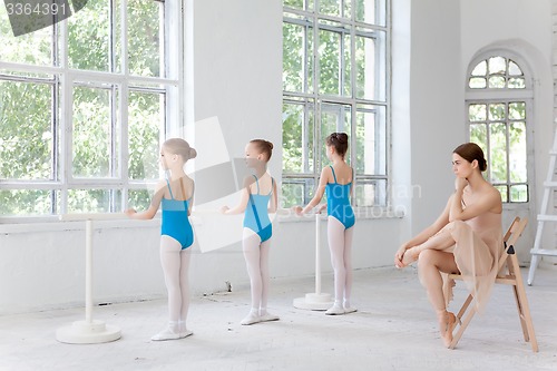 Image of Three little ballerinas dancing with personal ballet teacher in dance studio