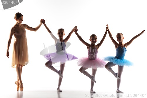 Image of Three little ballerinas dancing with personal ballet teacher in dance studio