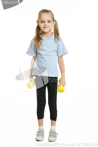 Image of Six year old girl athlete standing with dumbbells