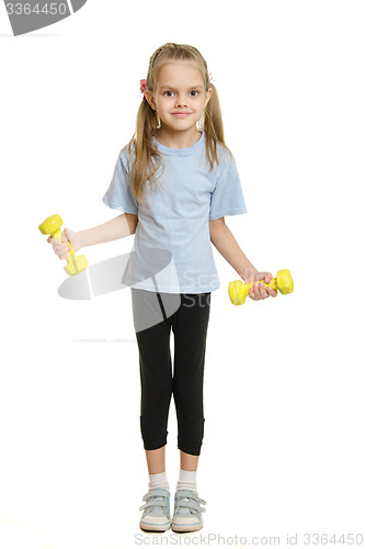 Image of Six year old girl athlete engaged in exercise with dumbbells