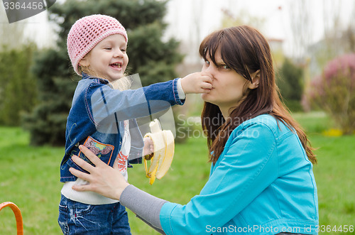 Image of Girl with banana mother pinched nose