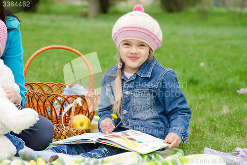 Image of girl of five years sitting on a green lawn