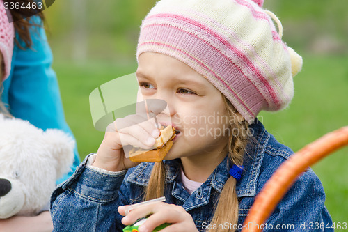 Image of Girl eating cake at a picnic