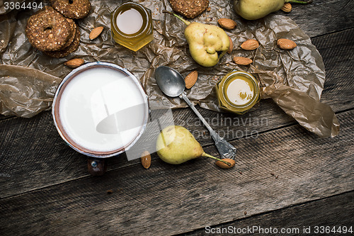 Image of Almonds pears Cookies and milk on wooden table