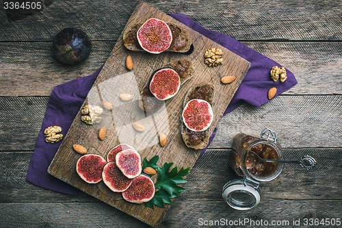 Image of figs, nuts and bread with jam on choppingboard in rustic style