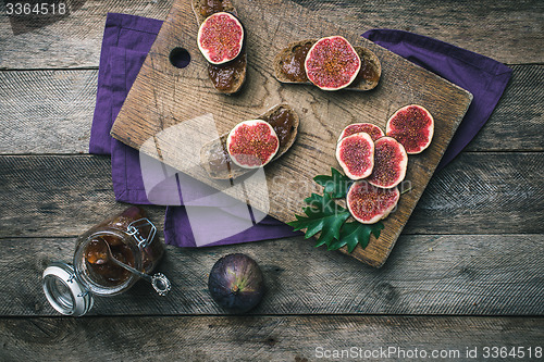 Image of Cut figs and bread with jam on choppingboard in rustic style