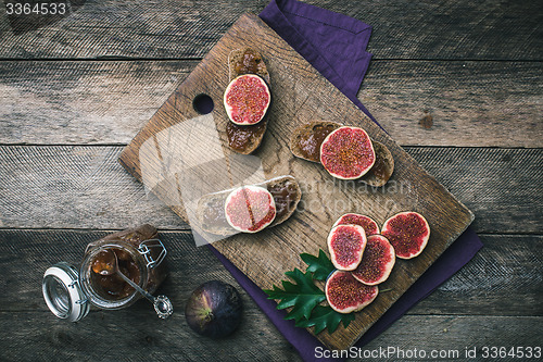 Image of Sliced figs and bread with jam on choppingboard in rustic style