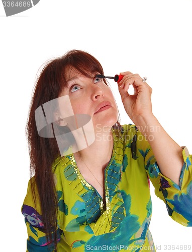 Image of Woman putting makeup on her eyelashes.