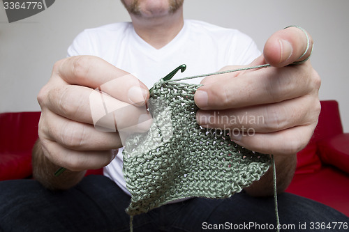Image of Closeup of a man knitting a scarf