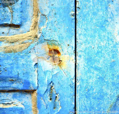 Image of stripped paint in the blue wood door and rusty nail