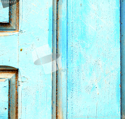 Image of stripped paint in the blue wood door and rusty nail