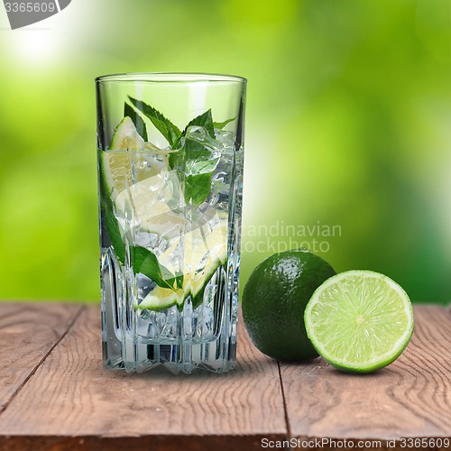 Image of mohito cocktail on wooden table against green background