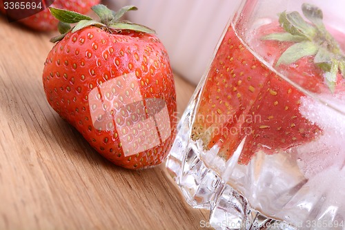 Image of Strawberry on wooden plate and strawberry frozen in ice cube