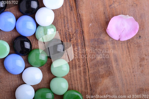 Image of spa stones and flower petals on wooden table, closeup